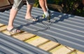 Roofing Construction. Roofer with crew gun installing  lightweight metal roof tiles roofing  construction on house roofing Royalty Free Stock Photo