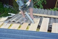 Roofing Construction. Roofer with electric saw cut wooden beams for  lightweight metal roof tiles installation Royalty Free Stock Photo