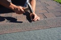 Roofing Construction. Roofer installing asphalt shingles on house construction roof corner with hammer and nails