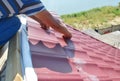 Roofing construction. Roofer installing metal roof sheets on the