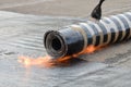 Roofing installation felt with heating and melting bitumen roll by torch on flame, closeup detail shoot