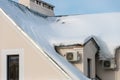 The roofs of the buildings are covered with snow and ice after a big snowfall. External split wall air conditioner compressor unit Royalty Free Stock Photo