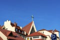 Roofs of the old european town. Big cross on the roof of Roman catholic church. Church steeple with blue sky Royalty Free Stock Photo