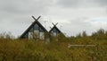 The roofs of two houses, which look like huts, look out from behind the trees