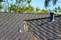A rooftop with asphalt shingles. A gutter filled with leaves and two ventilation pipes Royalty Free Stock Photo