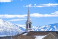 Rooftop of church with a modern spire design against snowy mountain and lake Royalty Free Stock Photo