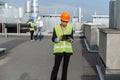 On the rooftop of construction site beautiful African engineer make a conversation with some worker using the tablet.