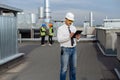 On the rooftop of construction site man engineer make a conversation with some worker using the tablet two workers are