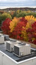 Rooftop HVAC units with autumn foliage in the background. highlighting the integration of technology and natural environment. Royalty Free Stock Photo