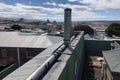 rooftop view of city, with downpipe being replaced and new pipe being installed