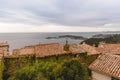 rooftops of houses on hill over seashore,