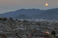 Rooftops in Lijiang old town and rising moon in the background, Yunnan