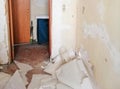 A room with bare walls and torn wallpaper, dirt, dust, debris