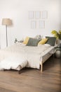 Room with a bed, yellow and green pillows, a light padded stool, a floor lamp and a framework on a wall Royalty Free Stock Photo