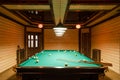 Room billiards decorated in dark wood with low lamps, billiard table with green cloth Royalty Free Stock Photo