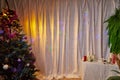 A room with a Christmas tree, a table and a curtain decorated for Christmas and New Year. A place for photo shoots in