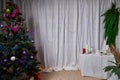 A room with a Christmas tree, a table and a curtain decorated for Christmas and New Year. A place for photo shoots in