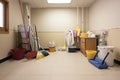 room with cleaning supplies, including mop bucket, broom, and dustpan