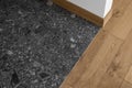 Room corner, three different textures: white wall, natural oak wood floor, stone dark grey tiles. Royalty Free Stock Photo