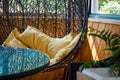 Room decor, cocoon chair with a yellow pillows, glass table, plants and wooden wall