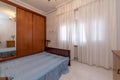 A room with a double bed without a mattress, a built-in wardrobe and a window with curtains Royalty Free Stock Photo