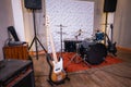 a room with a drum kit and electric bass guitar as well as a sound system