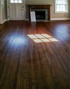 Room in empty house with no furniture and wood floors and a fireplace being gotten ready to rent...with reflection of window in th Royalty Free Stock Photo