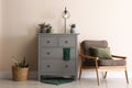 Room interior with grey chest of drawers near beige wall