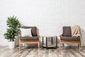 Room interior with modern armchairs and table near brick wall