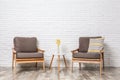 Room interior with modern armchairs and table white brick wall