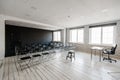 Room for lecture with a lot of dark chairs. Walls are white, loft interior. On the right there is a door. On the Royalty Free Stock Photo