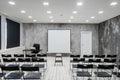 Room for lecture with a lot of dark chairs. Walls are white, loft interior. On the right there is a door. On the Royalty Free Stock Photo