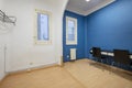 A room with an old window made of solid wood and glass, aluminum radiators with heating pipes on the wall, blue and white walls