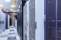 Room with rows of server hardware in big modern data center corridor. Technical equipment and supercomputers in cabinets under