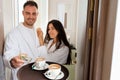 Room service delivering coffee to a hotel room for married couple wearing bathrobe who is giving dollar tips Royalty Free Stock Photo