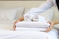 Room service maid cleaning and making bed hotel room concept, woman hands putting stack of fresh white bath towels on bed sheet Royalty Free Stock Photo