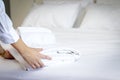 Room service maid cleaning and making bed hotel room concept, woman hands putting stack of fresh white bath towels on bed sheet Royalty Free Stock Photo