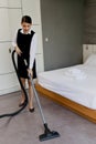 Room service maid cleaning and making bed hotel room concept, young beautiful Asian female chambermaid vacuuming the floor at Royalty Free Stock Photo
