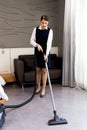 Room service maid cleaning and making bed hotel room concept, young beautiful Asian female chambermaid vacuuming the floor at Royalty Free Stock Photo