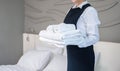 Room service maid holding clean folded white towels in hotel guest room Royalty Free Stock Photo