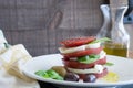 Closeup Caprese Salad with sliced red tomato, buffalo mozzarella, basil leaves and healthy whole olives dripping in extra virgin o Royalty Free Stock Photo