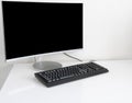 There is a monitor with a black screen and a non-black keyboard on a white table. Royalty Free Stock Photo