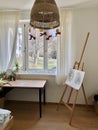 Room with window easel with artwork table chair