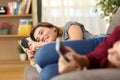 Roommates using their smart phones lying on a couch