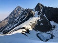 Roopkund lake with high cliffs covered in snow in the background in India