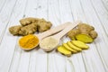 The root of the ginger entirely sliced, in wooden spoons crushed ginger and turmeric, on the table from light as.