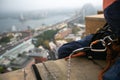 Rope access abseiler sitting over high rise building edge having hardware descender device clipping on 10.5 mm Dynamic low stretch