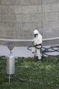 Worker wearing a protective gear cleaning a stone faceade in rope access