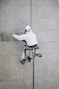 Worker wearing a protective gear cleaning a stone faceade in rope access