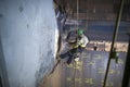 Rope access sandblaster worker wearing safety equipment harness working at height